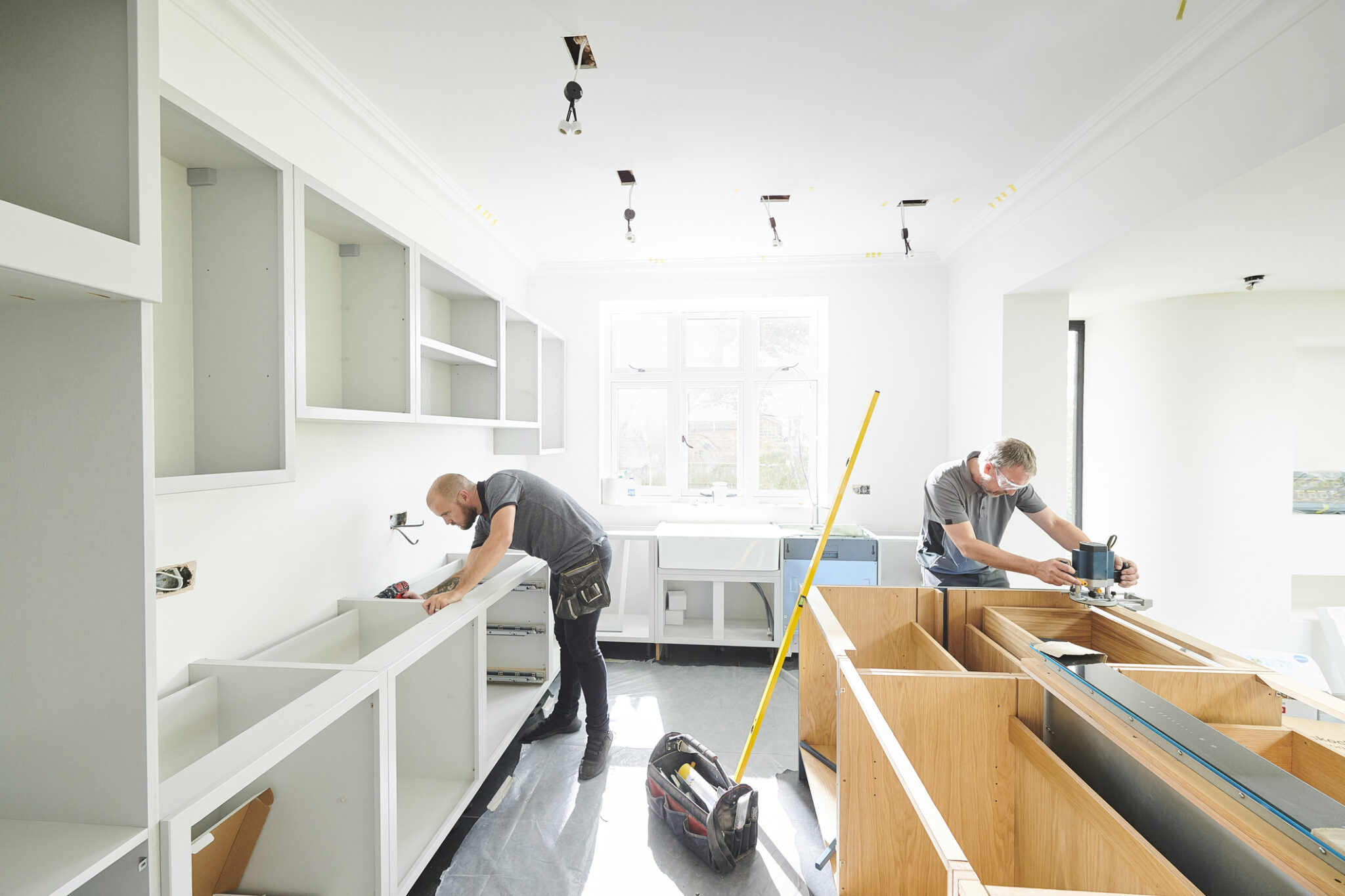 Kitchen renovation with two workers installing cabinets.