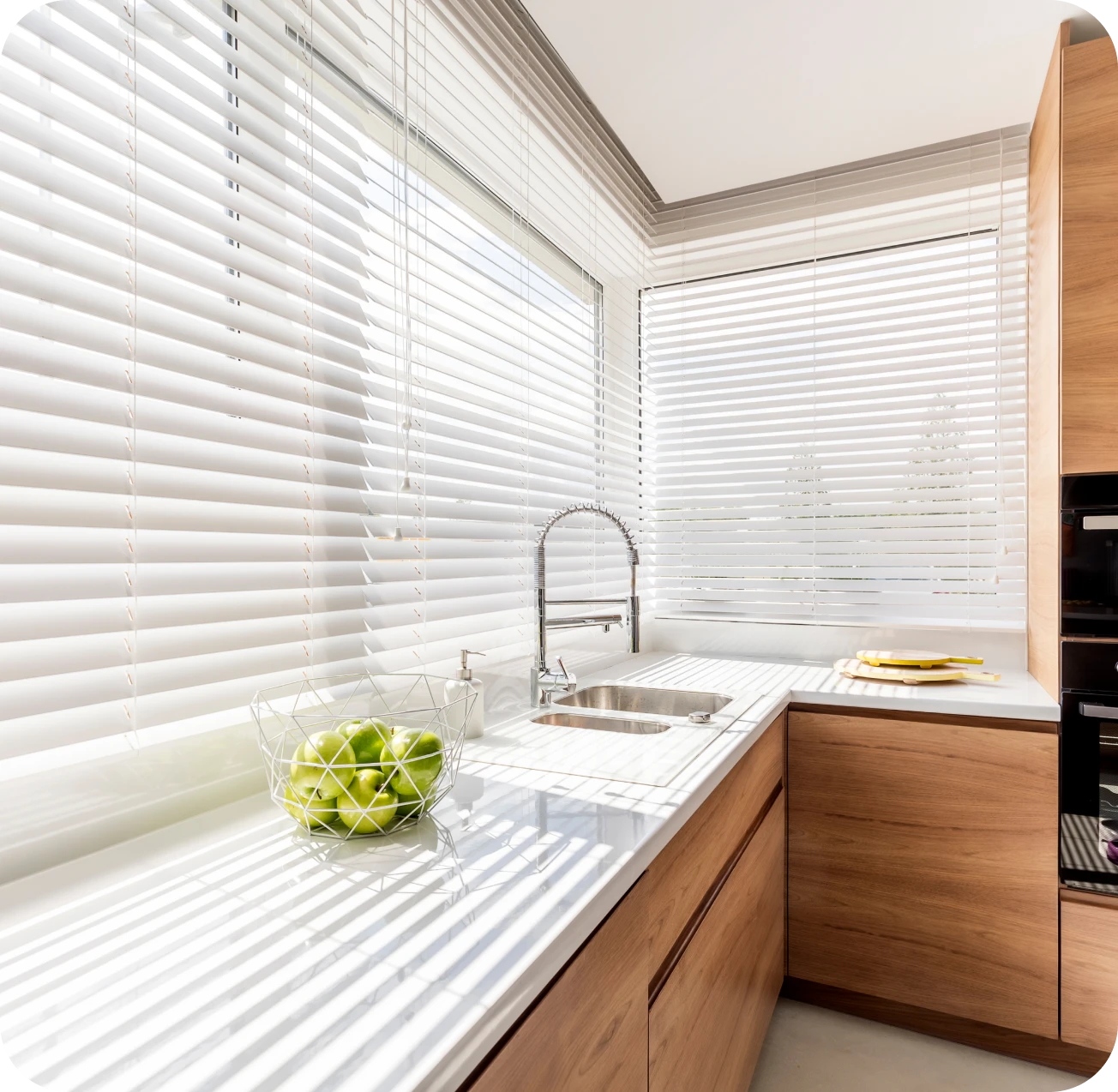 Modern kitchen with wooden cabinets and blinds.
