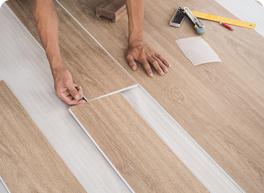 Man installing wooden laminate flooring panels.